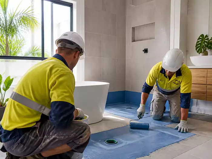 A team of waterproofing experts applying a moisture barrier in a Caloundra home