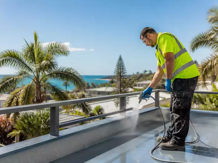 A waterproofing technician applying a sealant on a balcony in Mooloolaba
