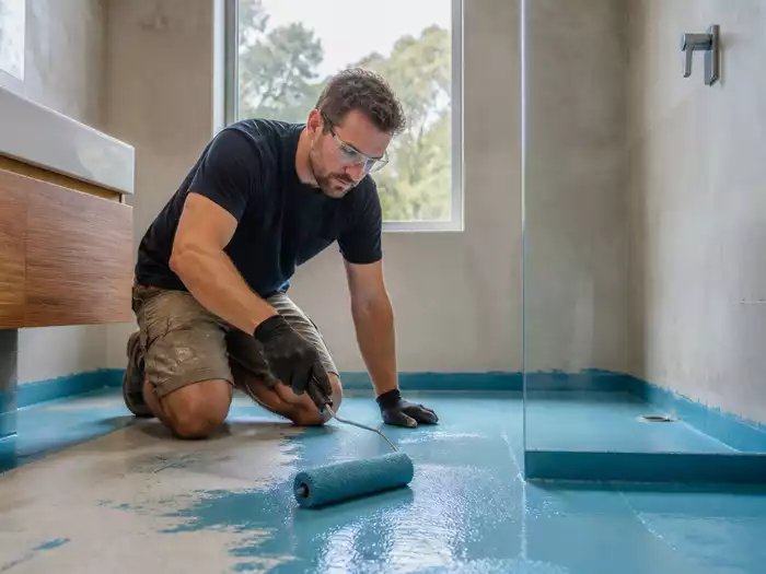 A professional applying waterproofing membrane in a Nambour home bathroom